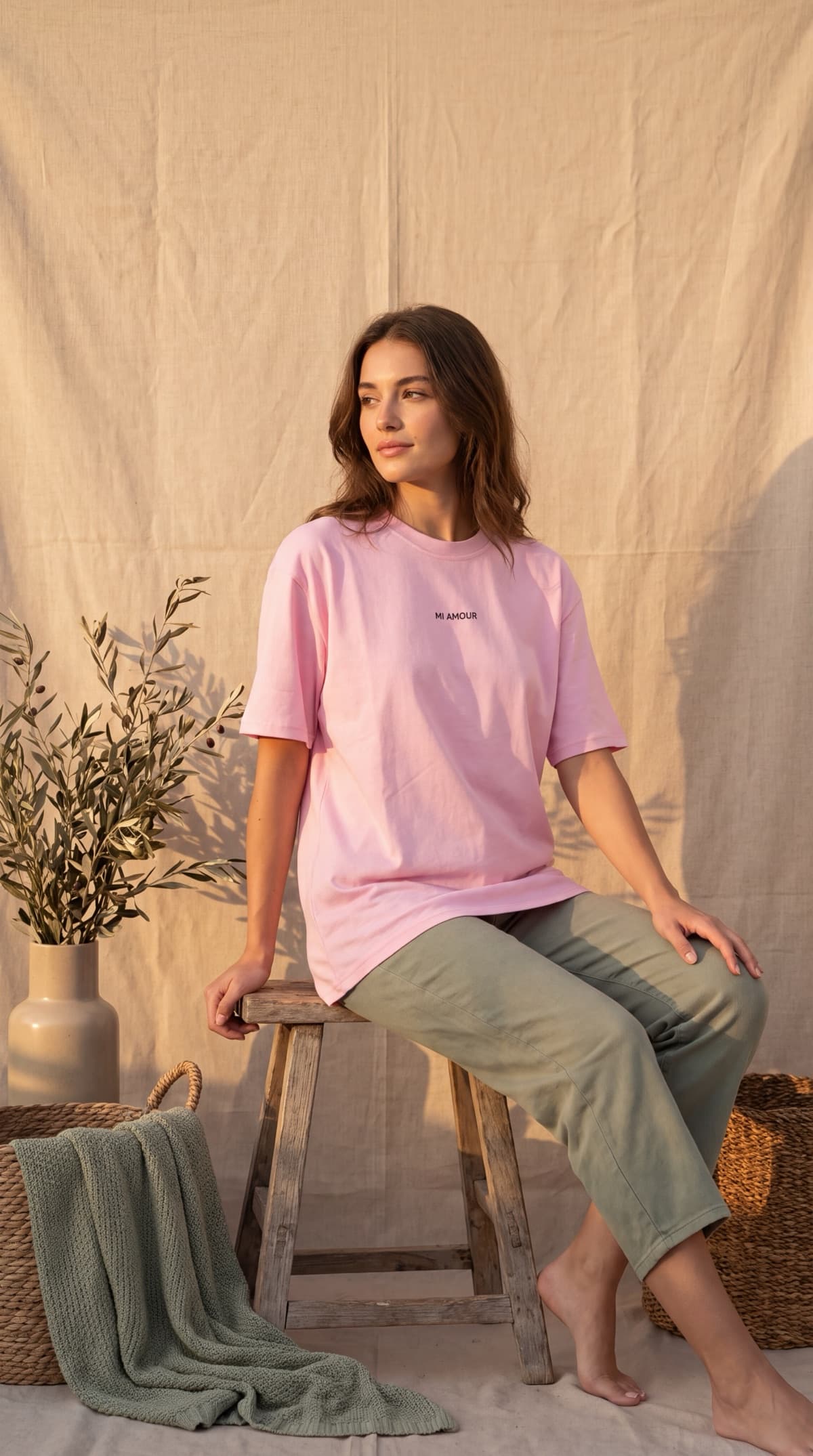 Visuel généré par Mireo : t-shirt rose Mi Amour porté, assise sur un tabouret, lumière du soir